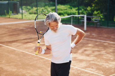 Travma yüzünden acı çekiyor. Son sınıf modern stil adamı gündüz vakti spor sahasında..