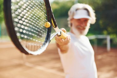 Oyun oynuyorum. Gündüz vakti tenis kortunda raketi olan son sınıf modern stil sahibi bir adam..