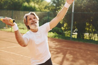 Oyun oynuyorum. Gündüz vakti tenis kortunda raketi olan son sınıf modern stil sahibi bir adam..