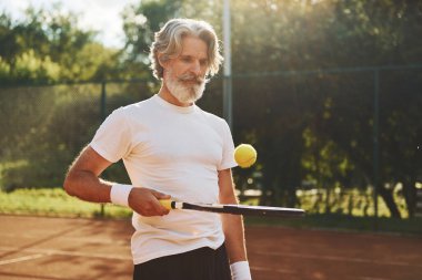 Eğitim zamanı. Gündüz vakti tenis kortunda raketi olan son sınıf modern stil sahibi bir adam..