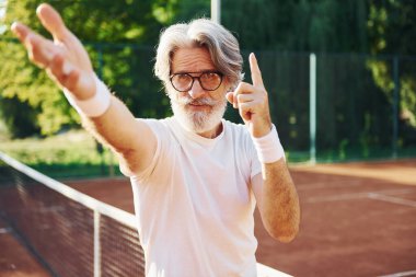 Kamera için poz vermek. Güneş gözlüklü. Son sınıf modern stil adamı gündüz vakti spor sahasında..