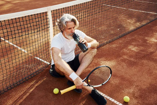 Water Drinken Grond Zitten Senioren Moderne Stijlvolle Man Met Racket — Stockfoto
