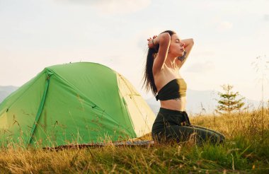 Genç bayan dinleniyor ve dağlarda yoga egzersizleri yapıyor..