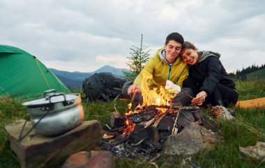 Kamp ateşinin yanında lokum yemiş bir çift. Majestic Karpat Dağları. Dokunulmamış doğanın güzel manzarası.