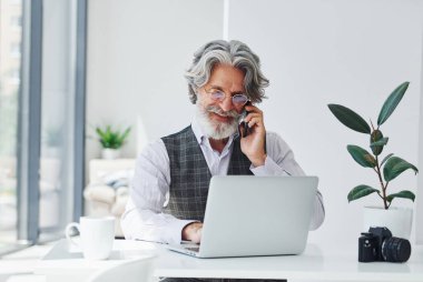 Resmi kıyafetli patron ofiste çalışıyor. Gri saçlı ve sakallı son sınıf modacı modern adam..