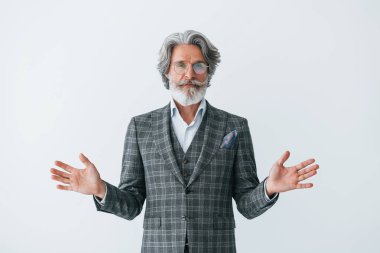 Zarif kıyafetler içinde. Beyaz duvara yaslanmış. Gri saçlı ve sakallı son sınıf modacı modern adam..