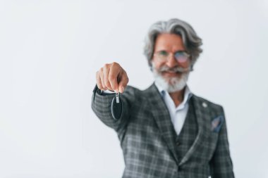 Arabanın anahtarlarını elinde tutuyor. Gri saçlı ve sakallı son sınıf modacı modern adam..