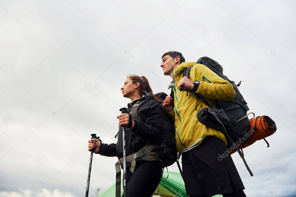 Young couple hiking outdoors together. Cloudy weather.