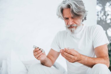 Midem bulanıyor. Yatakta. Gri saçlı ve sakallı son sınıf modacı modern adam..