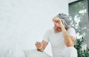 Midem bulanıyor. Yatakta. Gri saçlı ve sakallı son sınıf modacı modern adam..