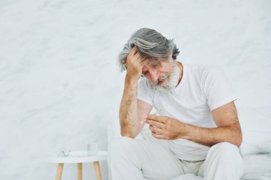 Midem bulanıyor. Yatakta. Gri saçlı ve sakallı son sınıf modacı modern adam..