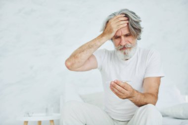 Midem bulanıyor. Yatakta. Gri saçlı ve sakallı son sınıf modacı modern adam..