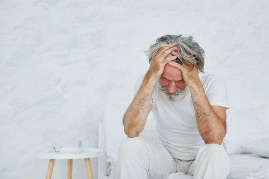 Midem bulanıyor. Yatakta. Gri saçlı ve sakallı son sınıf modacı modern adam..