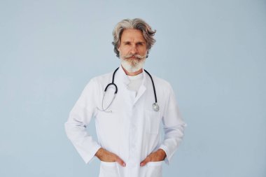 Duvara yaslanmış beyaz önlüklü doktor. Gri saçlı ve sakallı son sınıf modacı modern adam..