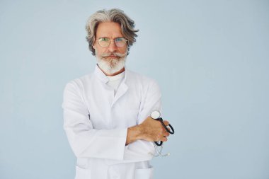 Duvara yaslanmış beyaz önlüklü doktor. Gri saçlı ve sakallı son sınıf modacı modern adam..