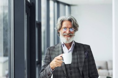 Ara veriyor ve kahve içiyor. Gri saçlı ve sakallı son sınıf modacı modern adam..