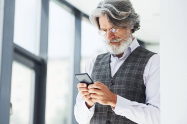 Başarılı bir iş adamı telefon kullanır. Gri saçlı ve sakallı son sınıf modacı modern adam..