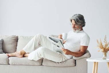 Kanepede dinleniyorum. Gri saçlı ve sakallı son sınıf modacı modern adam..