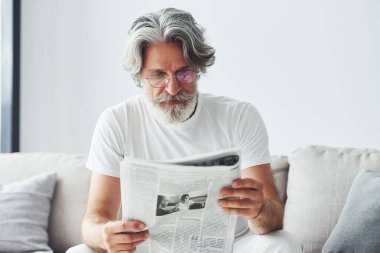 Kanepede dinleniyorum. Gri saçlı ve sakallı son sınıf modacı modern adam..