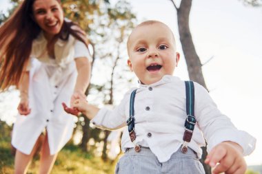 Birlikte eğleniyoruz. Küçük oğluyla birlikte genç bir anne ormanda. Güzel güneş ışığı.