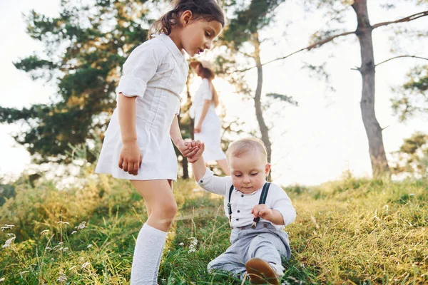 主婦は服を乾かす 幼い娘と息子を持つ若い母親は森の中に屋外にいます 美しい太陽 — ストック写真