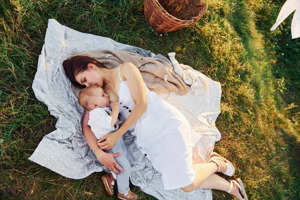 白い布の上に横になっている 幼い息子を持つ若い母親が森の中にいる 美しい太陽 — ストック写真