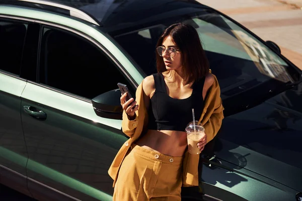コーヒーを飲みながら休憩する 若いですファッショナブルな女性でバーガンディ色のコートに昼間とともに彼女の車 — ストック写真