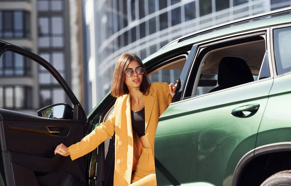 車を降りろ 若いですファッショナブルな女性でバーガンディ色のコートに昼間とともに彼女の車 — ストック写真