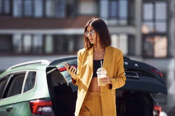 コーヒー休憩 若いですファッショナブルな女性でバーガンディ色のコートに昼間とともに彼女の車 — ストック写真
