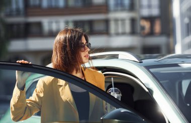 - Kapıyı açar. Gündüz vakti arabasıyla bordo renkli ceketli, şık bir kadın..