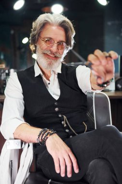 Berber dükkanı ekipmanları var. Gri saçlı ve sakallı modern son sınıf öğrencisi içeride..