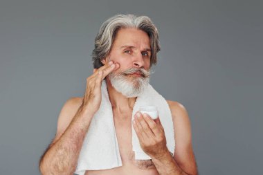 Yüz ve cilt temizliği ile ilgileniyor. Gri saçlı ve sakallı modern son sınıf öğrencisi içeride..