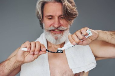 Diş macunu kullanıyorum. Gri saçlı ve sakallı modern son sınıf öğrencisi içeride..