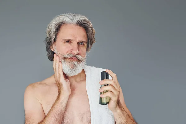 Fresh and clean face. Stylish modern senior man with gray hair and beard is indoors.