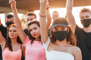 Yumruklar yükseğe fırladı. Birlikte duran bir grup protestocu genç. İnsan hakları eylemcisi veya hükümete karşı..