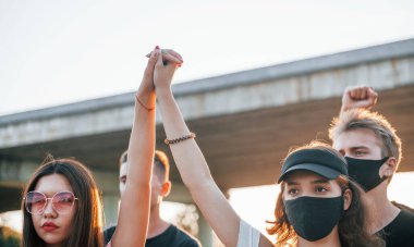 Yumruklar yükseğe fırladı. Birlikte duran bir grup protestocu genç. İnsan hakları eylemcisi veya hükümete karşı..
