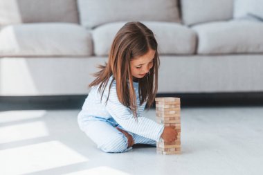 Kule oyunu oynuyor. Evde yalnız başına sevimli küçük bir kız. Çocuk hafta sonu eğleniyor.