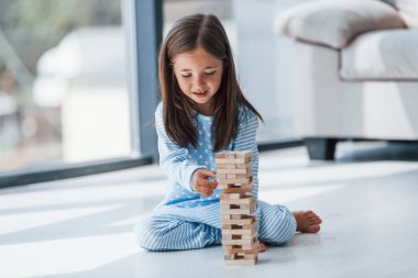 Kule oyunu oynuyor. Evde yalnız başına sevimli küçük bir kız. Çocuk hafta sonu eğleniyor.