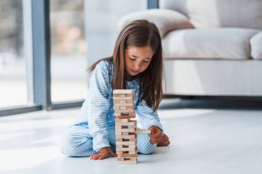 Kule oyunu oynuyor. Evde yalnız başına sevimli küçük bir kız. Çocuk hafta sonu eğleniyor.