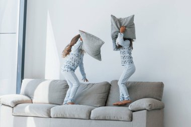 Yastık savaşı. Evde birlikte oturan iki küçük tatlı kız. Çocuklar eğleniyor..