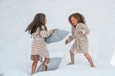 Ellerinde yastıklarla. Evde birlikte oturan iki küçük tatlı kız. Çocuklar eğleniyor..