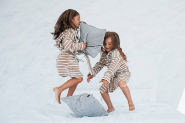 Ellerinde yastıklarla. Evde birlikte oturan iki küçük tatlı kız. Çocuklar eğleniyor..