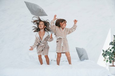 Ellerinde yastıklarla. Evde birlikte oturan iki küçük tatlı kız. Çocuklar eğleniyor..