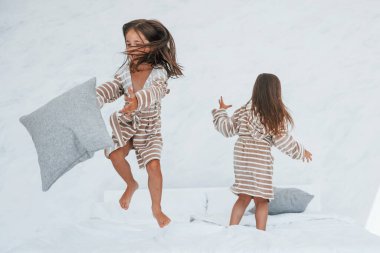 Ellerinde yastıklarla. Evde birlikte oturan iki küçük tatlı kız. Çocuklar eğleniyor..