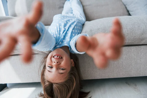 Kanepede baş aşağı yatıyordu. Evde yalnız başına sevimli küçük bir kız. Çocuk hafta sonu eğleniyor.