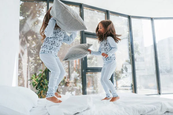 Yastık savaşı. Evde birlikte oturan iki küçük tatlı kız. Çocuklar eğleniyor..