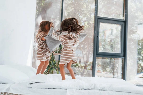 Ellerinde yastıklarla. Evde birlikte oturan iki küçük tatlı kız. Çocuklar eğleniyor..