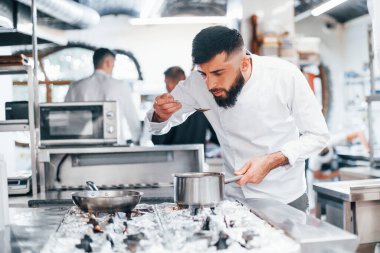 Mutfakta yemek pişiren beyaz üniformalı bir şef. İşte yoğun bir gün..