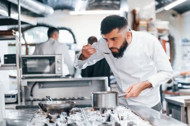 Mutfakta yemek pişiren beyaz üniformalı bir şef. İşte yoğun bir gün..