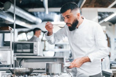Mutfakta yemek pişiren beyaz üniformalı bir şef. İşte yoğun bir gün..
